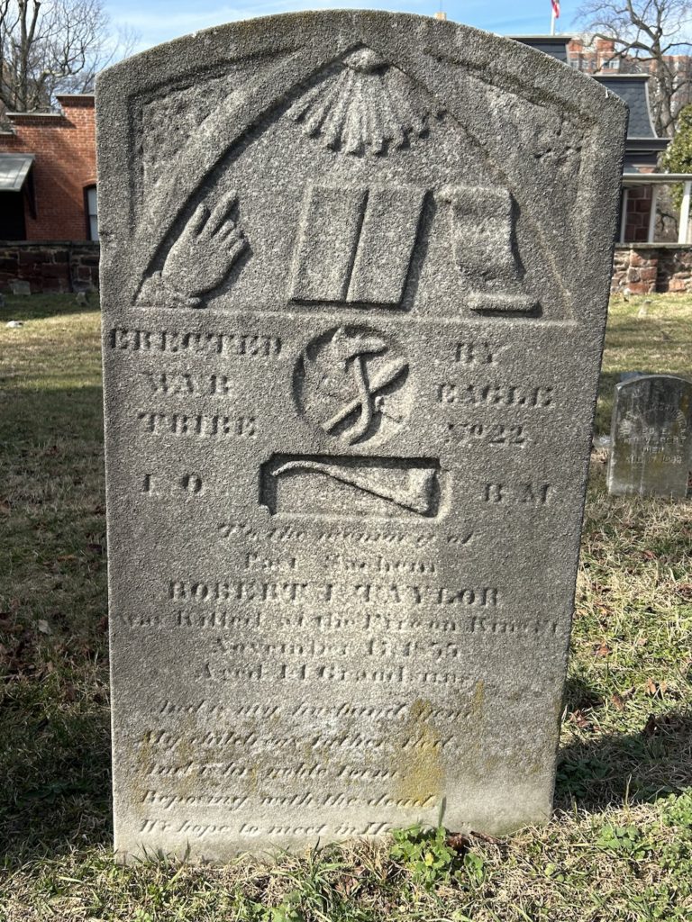 Gravestone of Robert I. Taylor in the Methodist Protestant Cemetery, featuring symbols of the Improved Order of Red Men and a Maltese Cross, honoring his service as a firefighter.