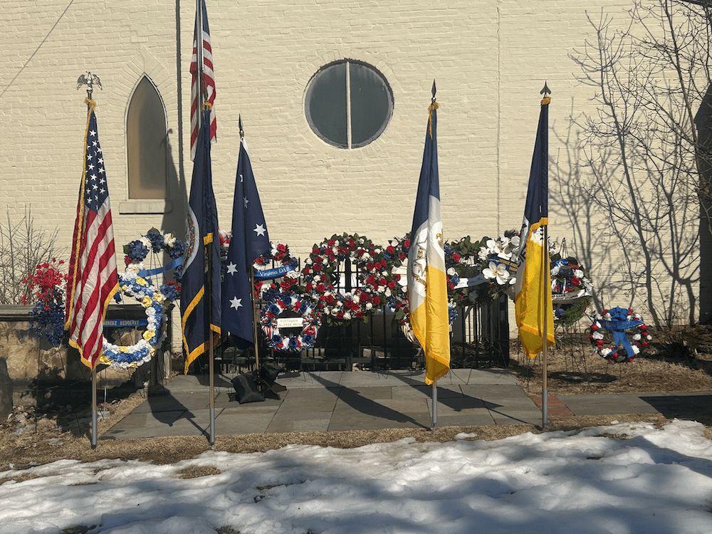 Tomb of the Unknown Soldier of the American Revolution at the Old Presbyterian Meeting House in Alexandria, Virginia, surrounded by patriotic wreaths and American and Virginia flags during the February 14, 2026 Wreath Laying Ceremony.